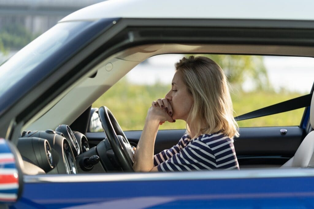 Frustrated female driver sit inside car with chin on hands scared to drive after vehicle accident