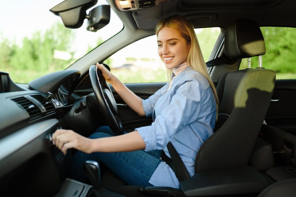 Smiling female student in the car, driving school